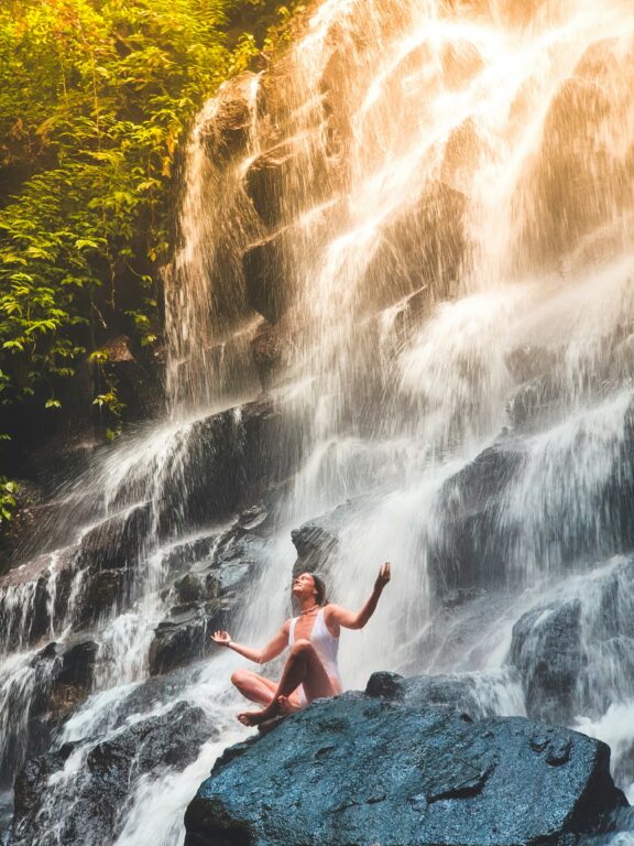 A woman in white monokini sitting on rock at Kanto Lampo Waterfall