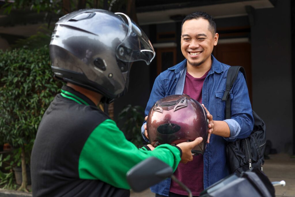 motorbike taxi driver giving helmet to passenger 2023 11 27 05 03 38 utc