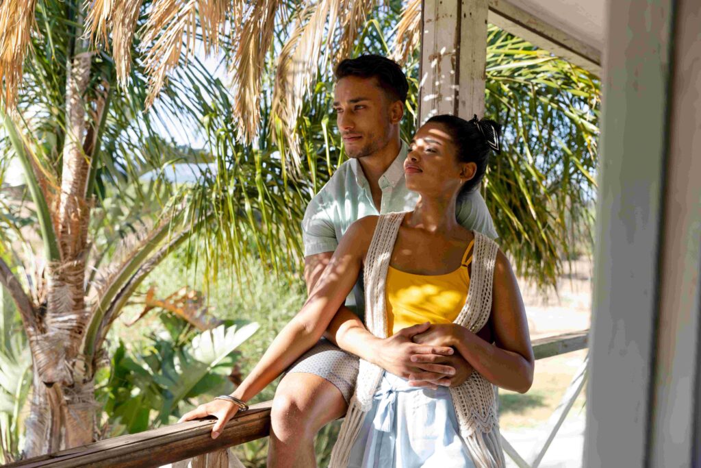 Caucasian young man hugging woman from back and looking away in balcony at cottage Unaltered, love, together, vacation, tourist resort, thoughtful, lifestyle and enjoyment concept