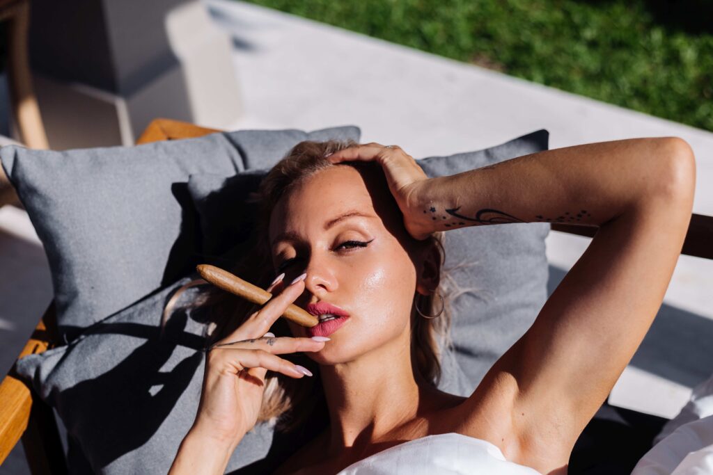 Fashion outdoor portrait of naked woman sit on sofa cover herself with blanket holding cigar