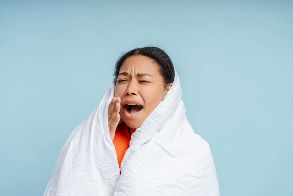 Yawning woman relaxing at home wrapped in soft blanket