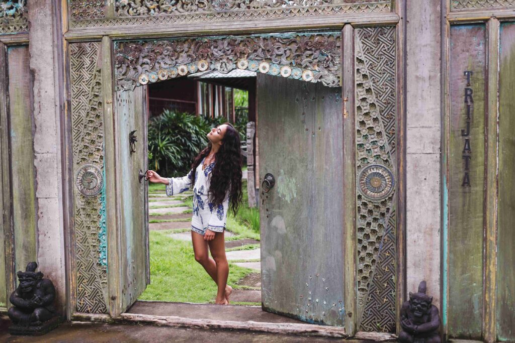 Young beautiful woman walking near old antique house in Bali sty