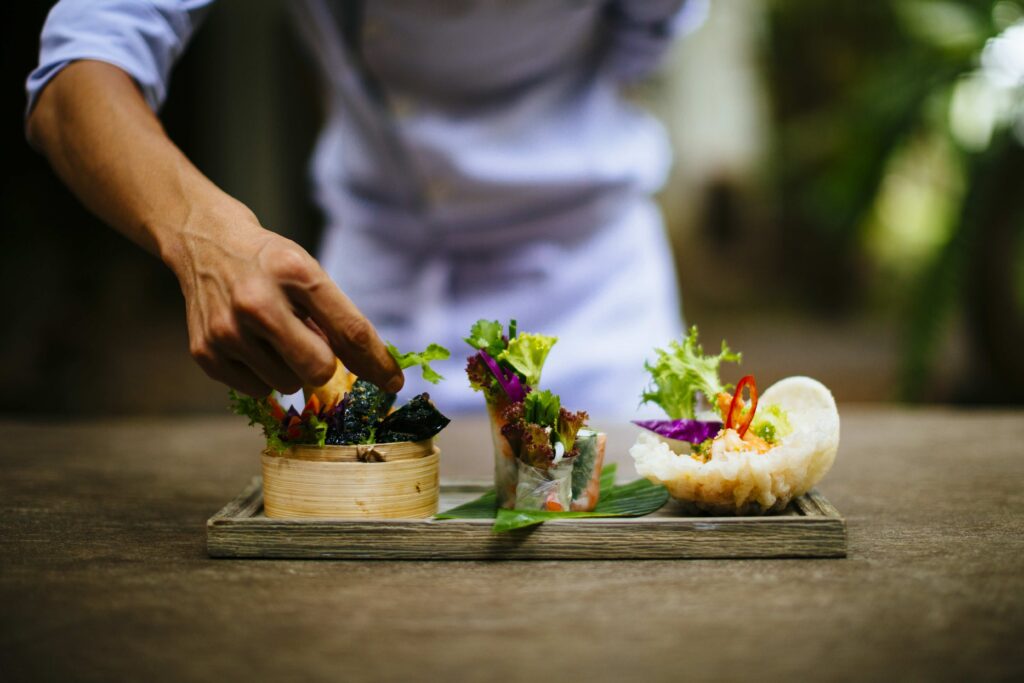 Close up of chef putting the final touches on a dish of salads and spring rolls ,Saigon