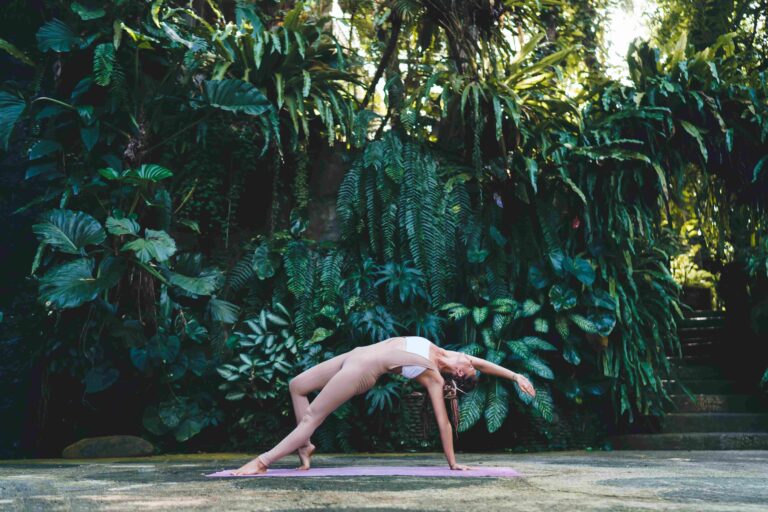 Frontal view of female in sportive tracksuit exercising during pilates slimming at nature with greenery, flexible fit girl reaching healthy lifestyle and wellbeing vitality while stretching during yoga