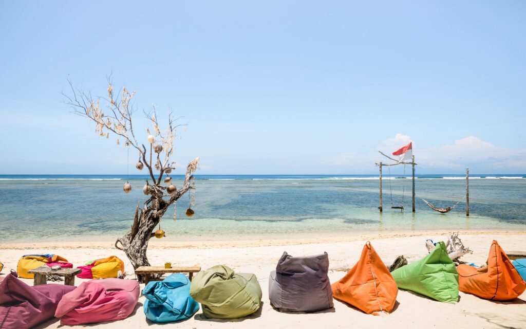 Gili Trawangan beach on a sunny day with multicolored sofas at c