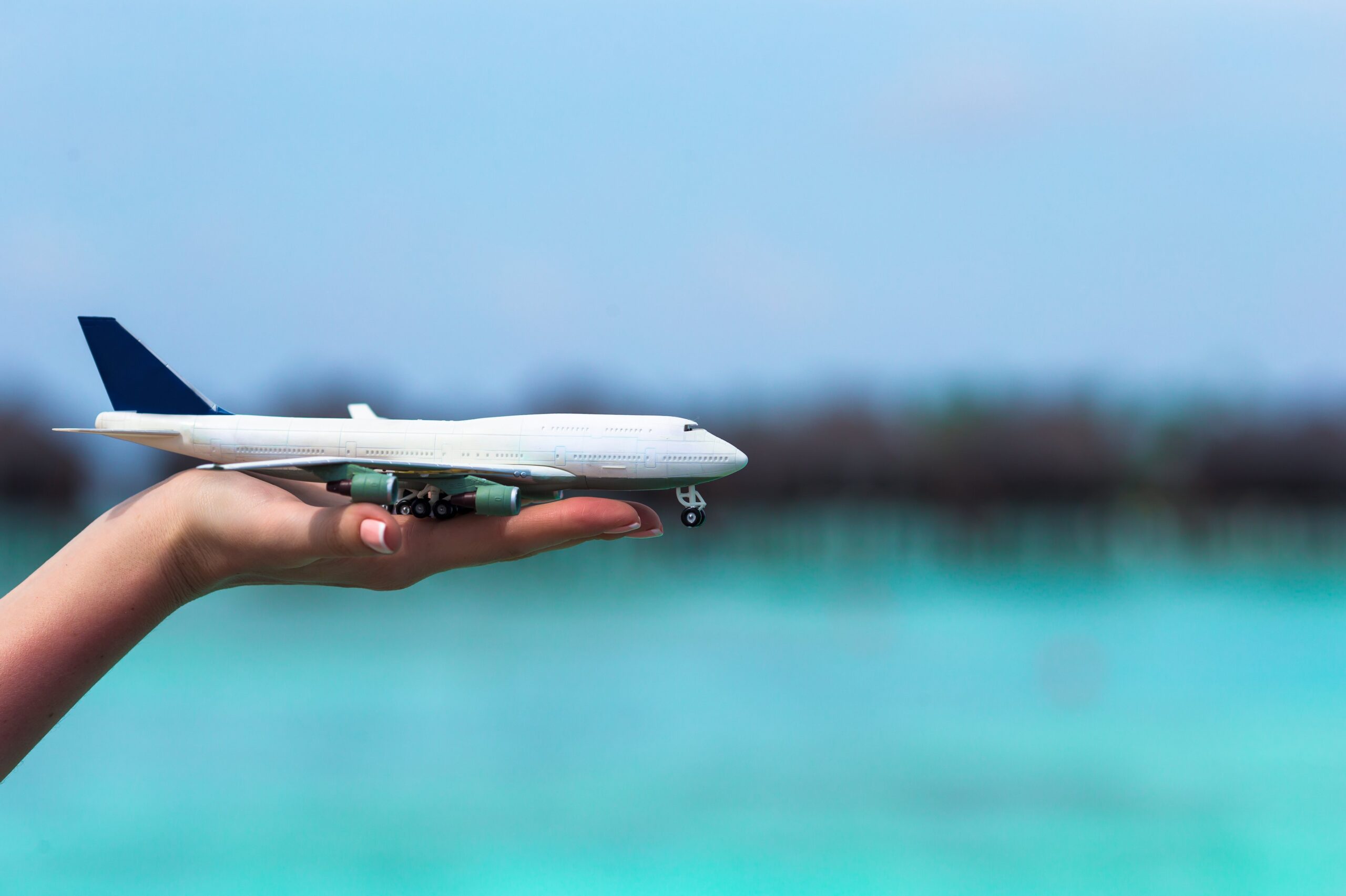 Little white toy airplane on background of turquoise sea