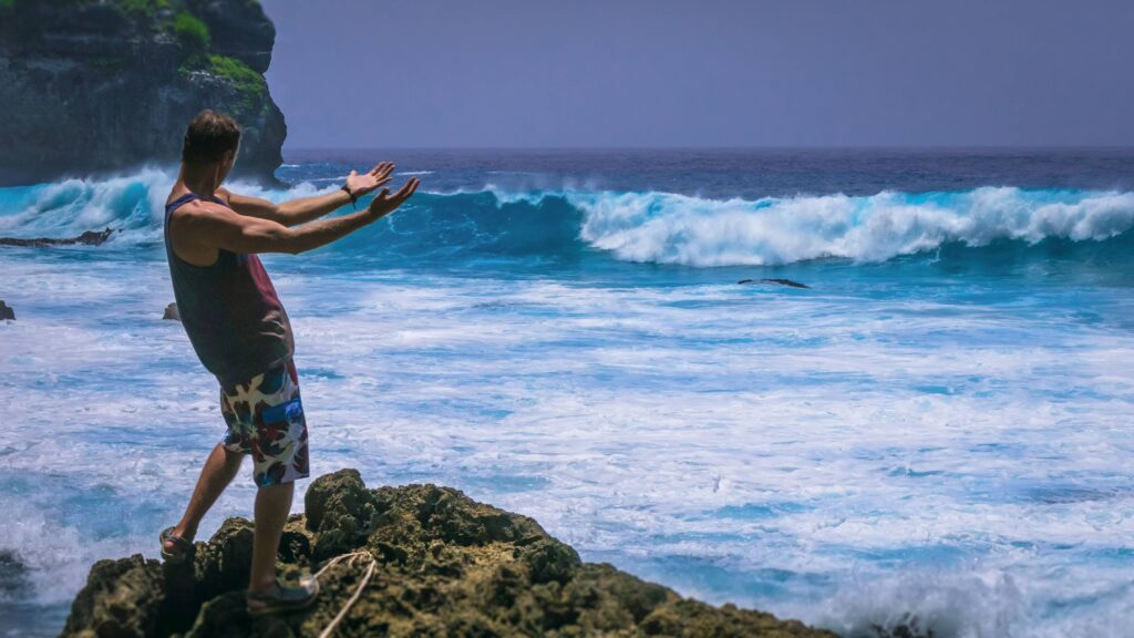 Man Provoke Ocean Waves on Tembeling Coastline at Nusa Penida island, Bali Indonesia