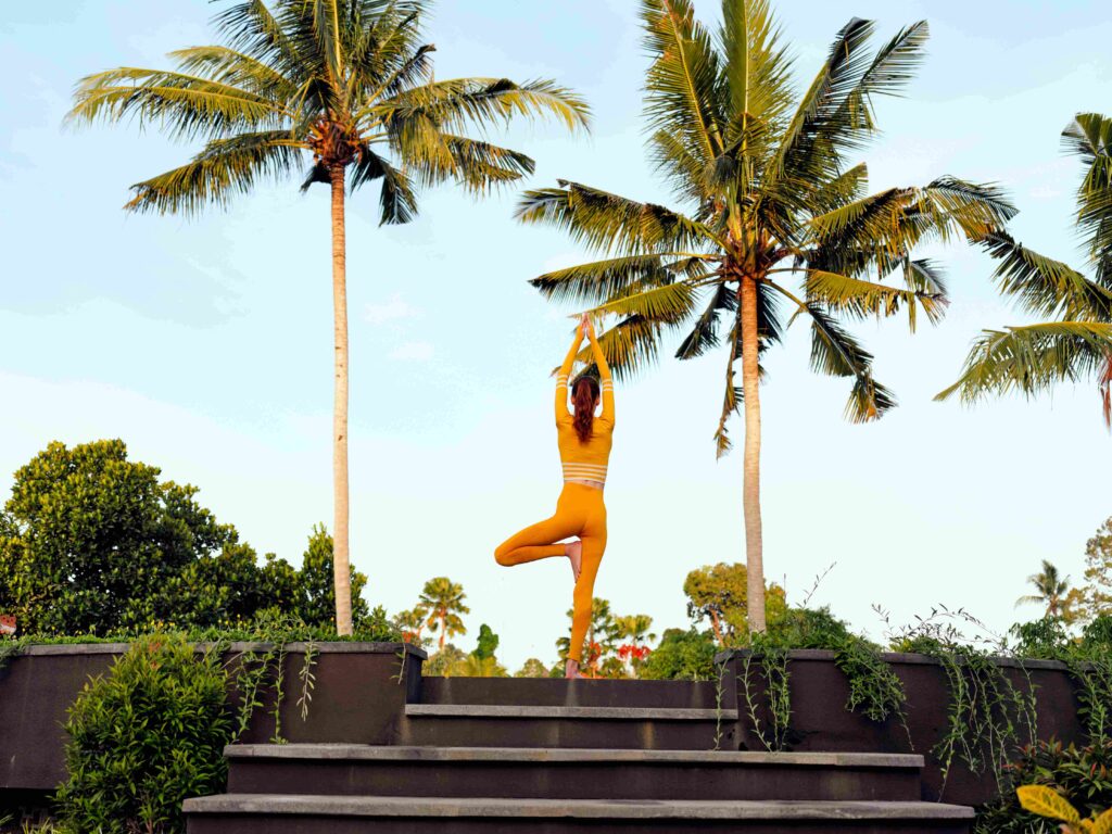 Relaxing yoga session in tropical paradise with woman in yellow outfit surrounded by palm trees and steps