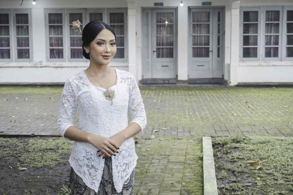 A young Indonesian woman with a happy expression wearing a white kebaya Kartini's Day Concept