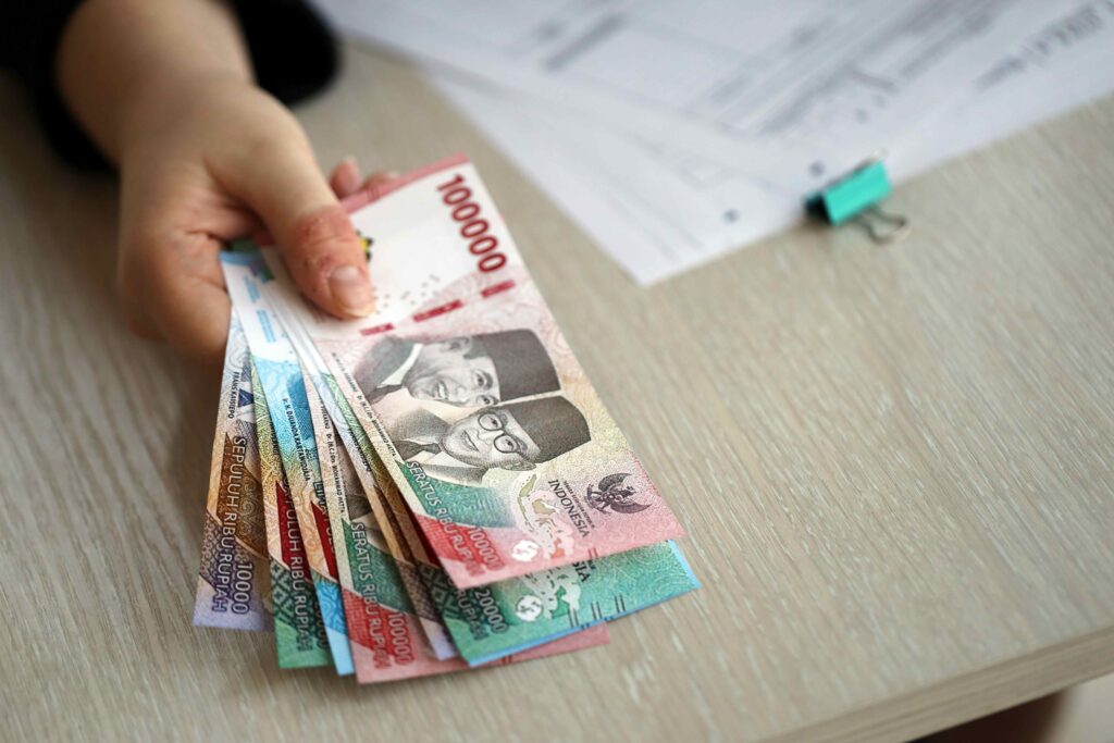 Female accountant hand give bunch of many indonesian rupiah money bills of new series