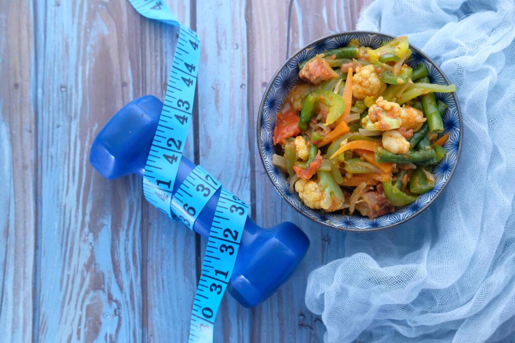 Fresh homemade salad in a plate with dumbbell on table