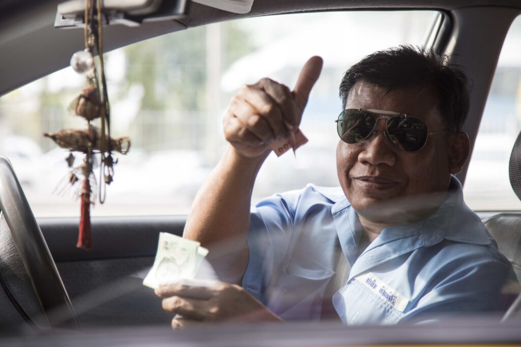 Friendly taxi driver giving a thumbs up through the car window