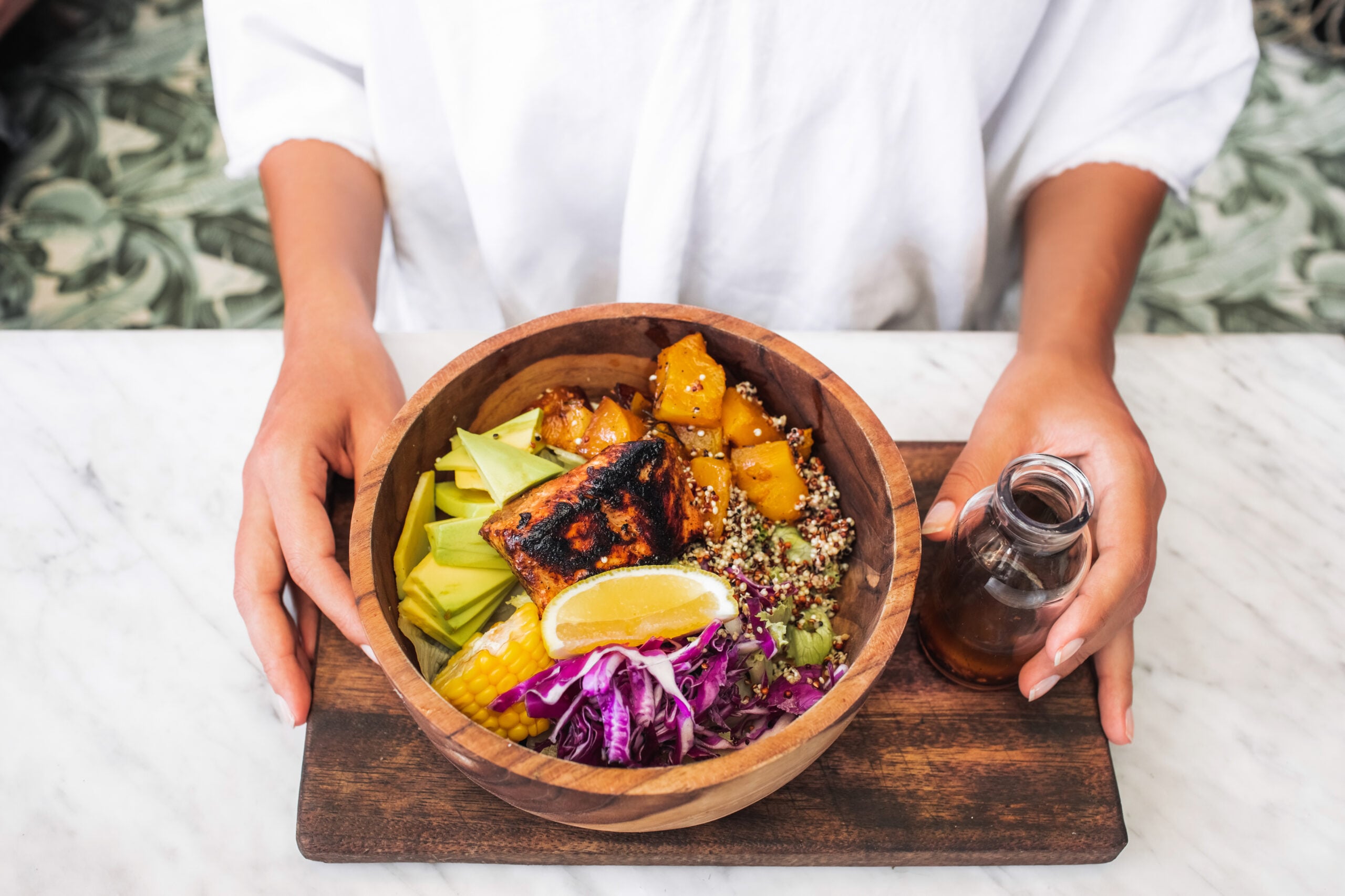 Woman eating meal with fried salmon fish steak, quinoa, avocado,