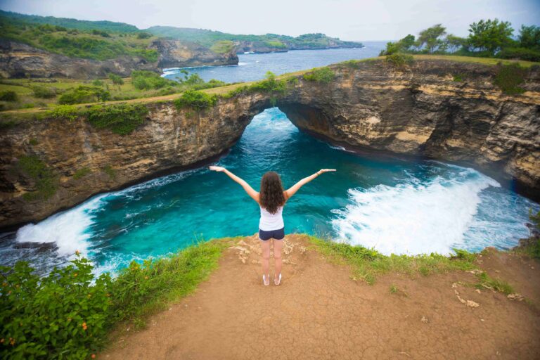 Young woman in Broken beach is beautiful rock coastline in Nusa Penida island nex to Bali