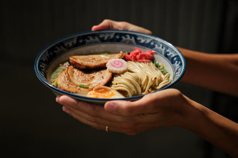 Crop woman showing bowl of ramen under sunlight