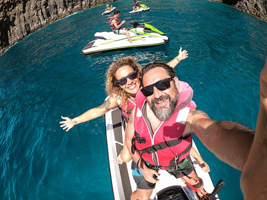 Happy adult couple have fun on jet sky activity escursion in summer holiday vacation at the sea ocean active people take selfie picture and smile with happiness and freedom cheerful lifestyle