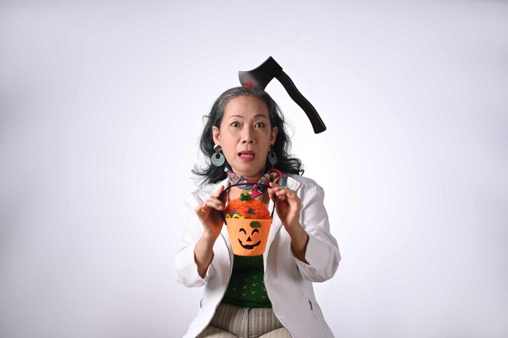 Happy senior woman dressed in halloween costume holding a pumpkin on white background