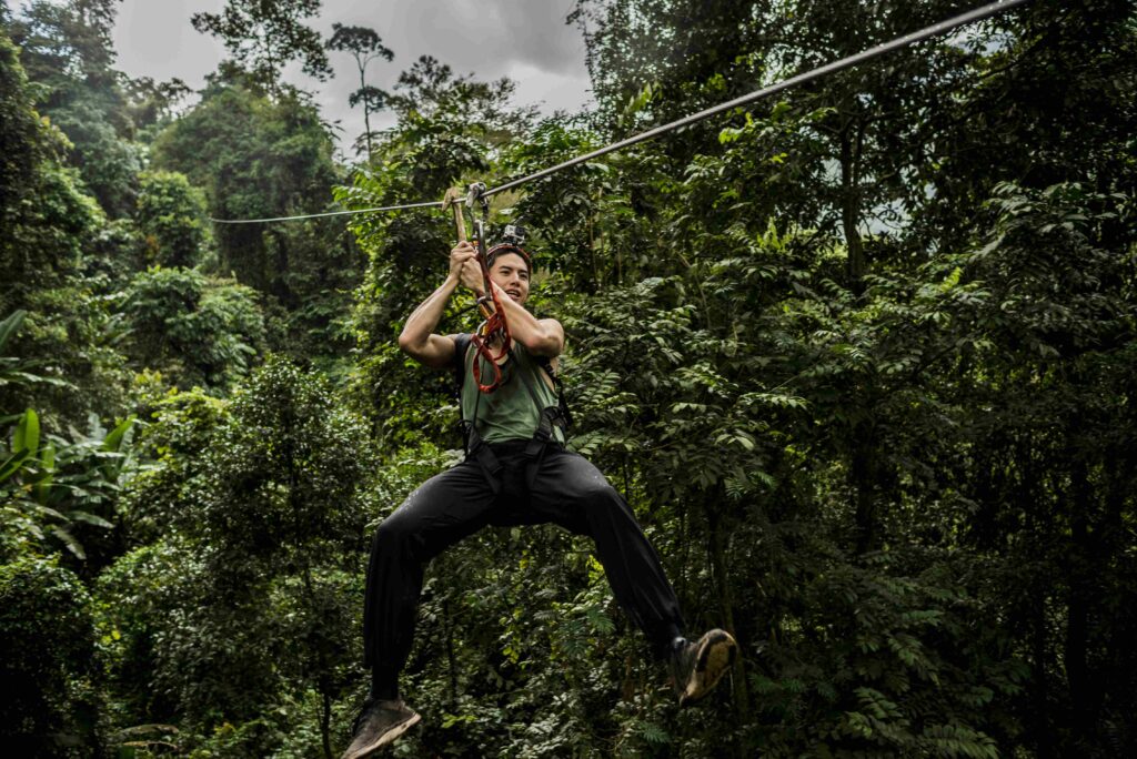 Man on zip wire in forest, Ban Nongluang, Champassak province, Paksong, Laos