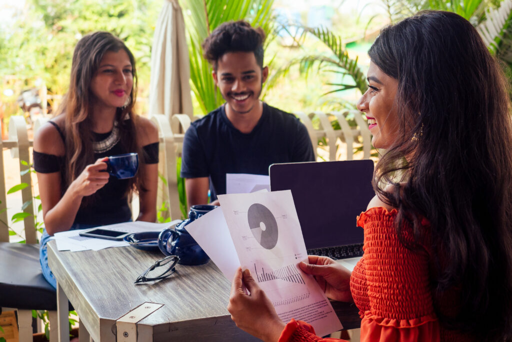 Multicultural group of people discussing by laptop in summer caf