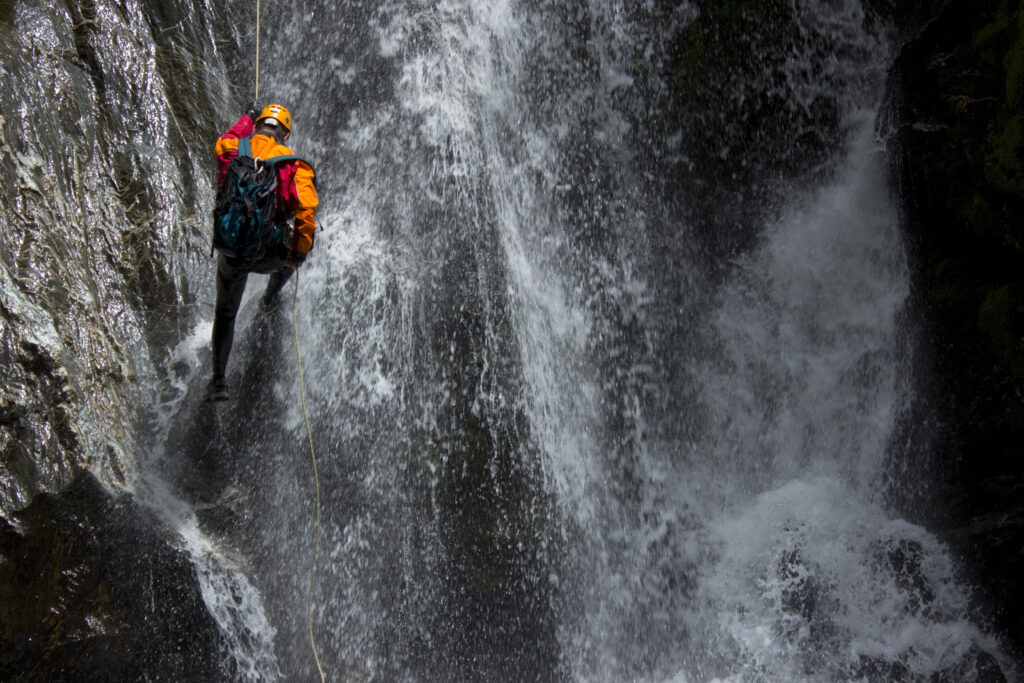 Person climbing up a waterfall in a forest