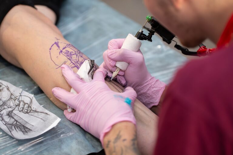 Tattoo machine A tattoo Master in a mask and gloves creates a pattern on the skin of a woman