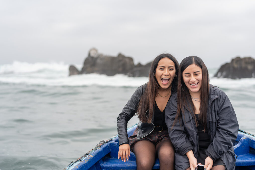 Two friends laughing while sitting on a boat in a cloudy day