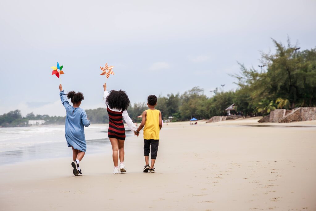 Back side of Happy Group of African American kids wind turbine toy on the beach