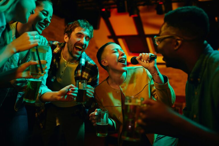 Cheerful friends having fun while singing karaoke during their night out in a pub