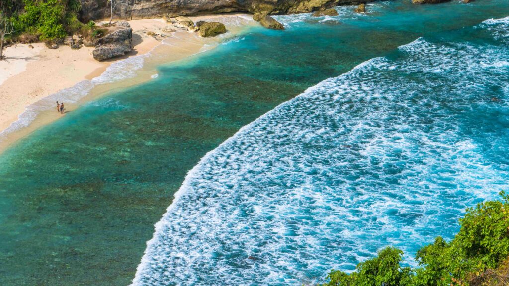 Couple on beautiful Atuh Beach with White Long Waves, Nusa Penida, Bali, Indonesia