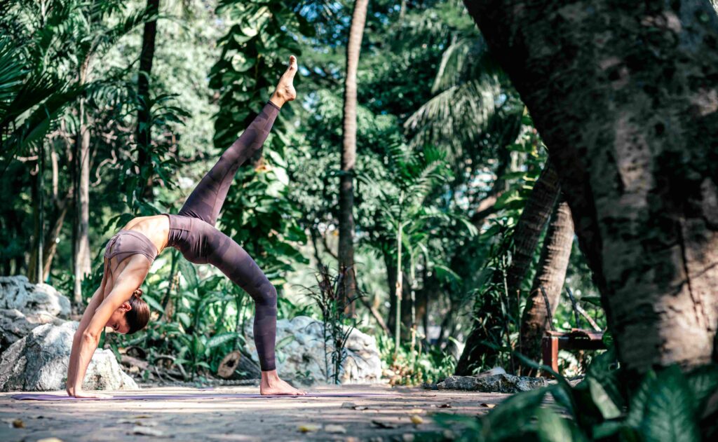 Cultivate a beautiful body Full length shot of caucasian woman standing in Wheel pose, Chakrasana while practicing yoga outdoors, in a garden Healthy lifestyle and relaxation concept