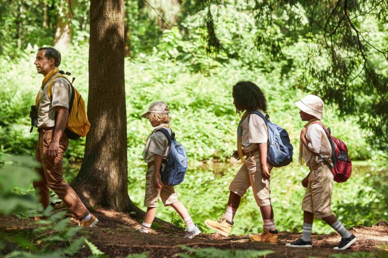 Side view at diverse group of scouts hiking lit by sunlight