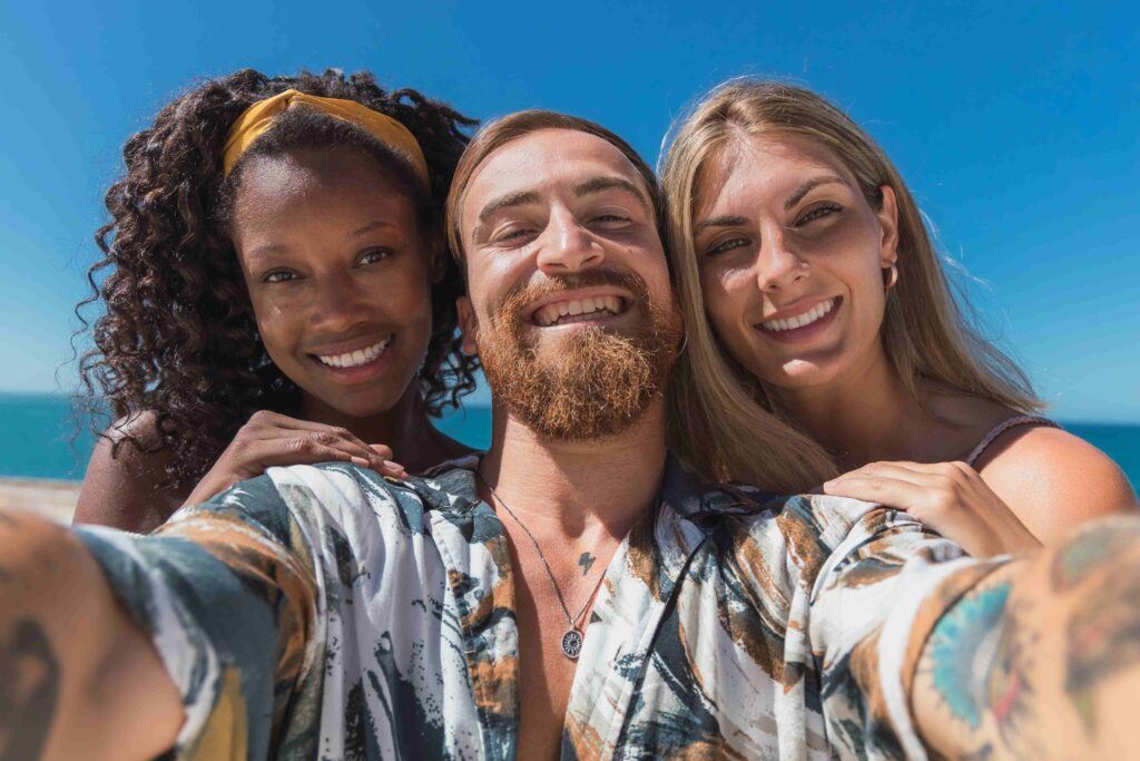 Multiethnic friends taking selfie against blue sky