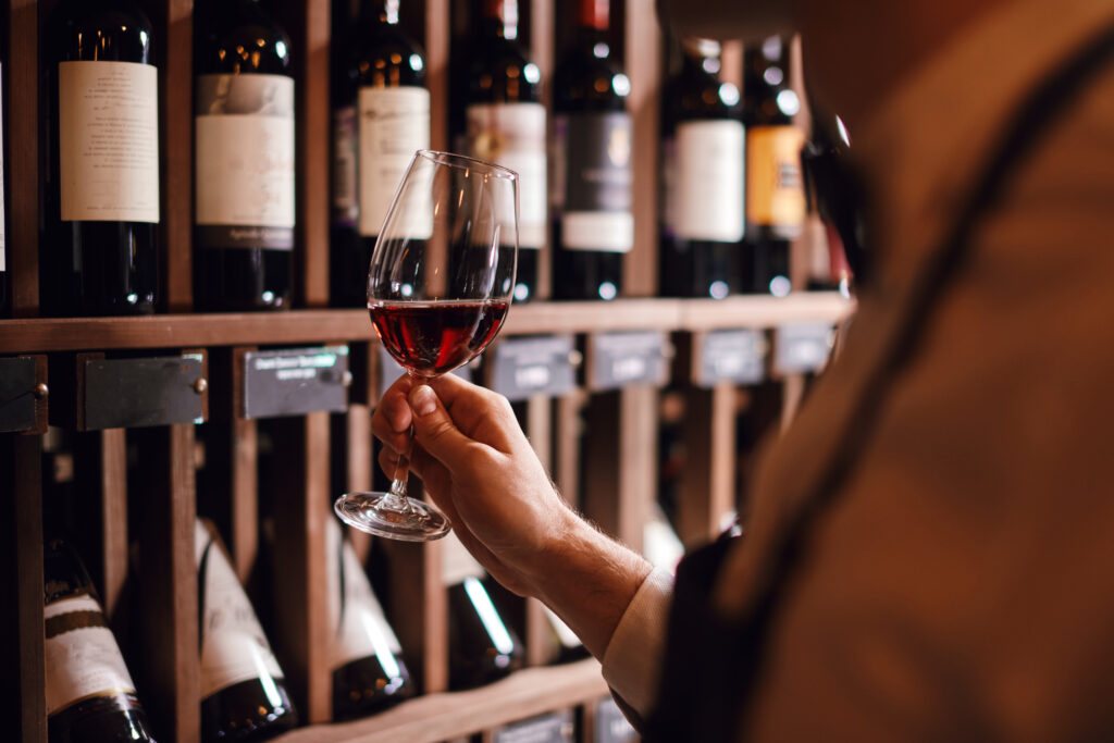 Wine expert holds a glass of wine, looks at tint and smells flavor, degustating