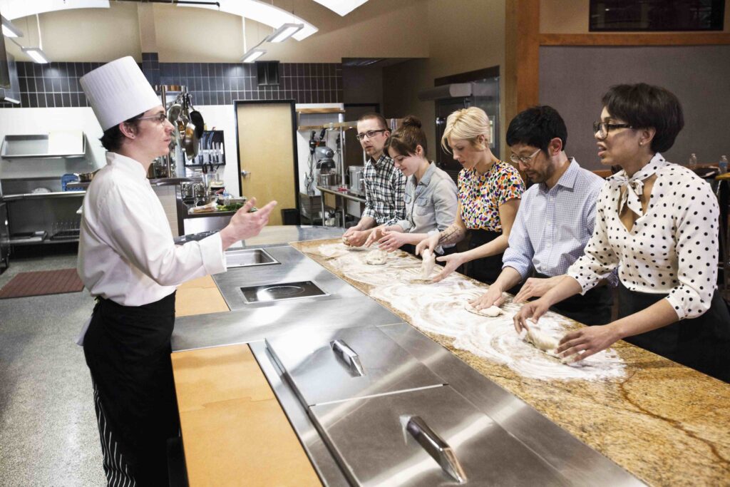 A caucasian male chef teaching a cooking class, multi ethnic group