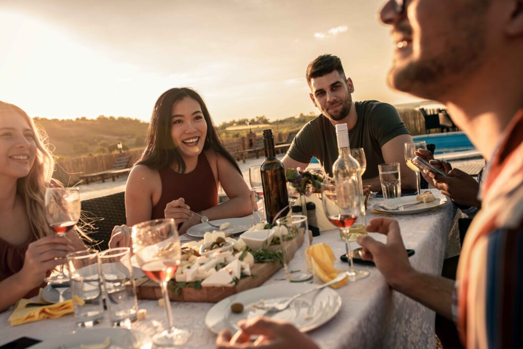 Diverse group of friends at reunion eating and drinking wine out