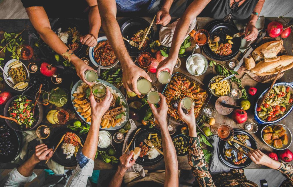 Flat lay of family clinking glasses over table with Turkish foods