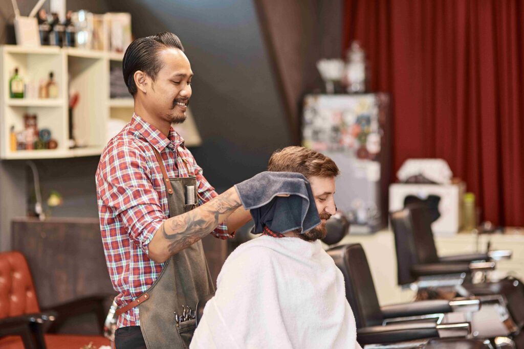 Positive thai hairdresser providing best service for a bearded man