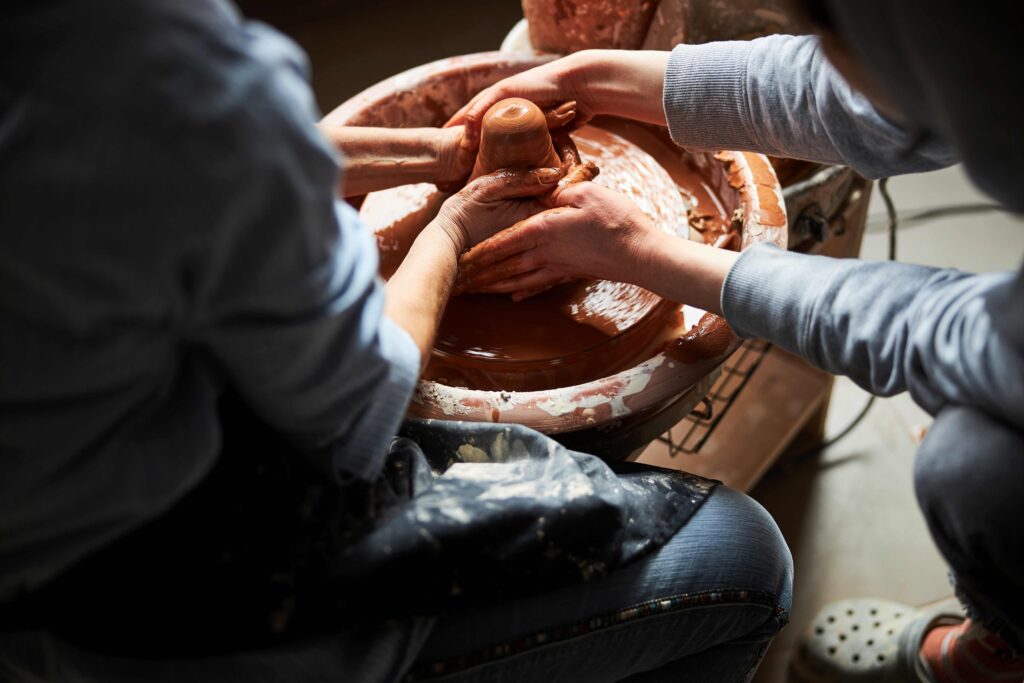 Potters hands making clay pot in workshop