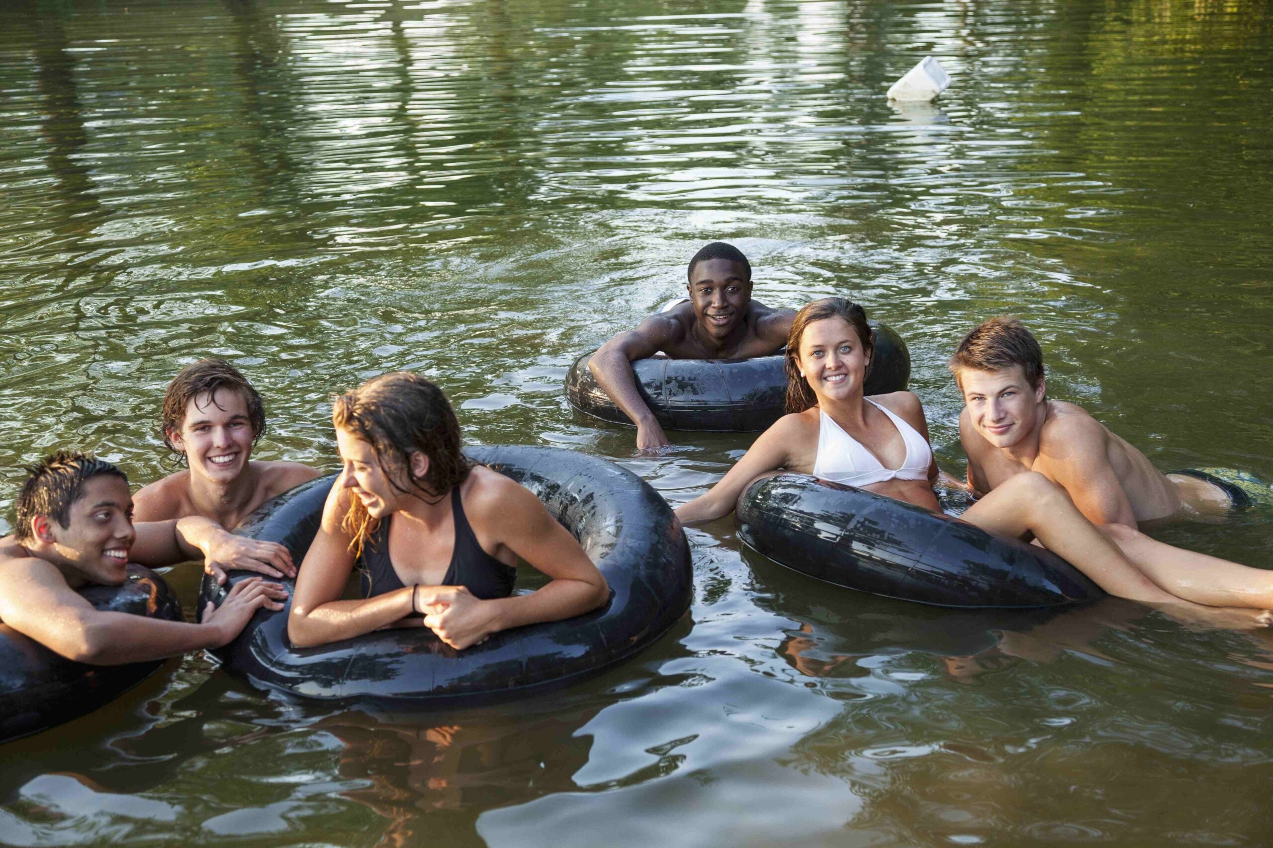 One Straw Farm,USA,A group of young people, boys and girls, swimming and floating using swim floats and inflated tyres