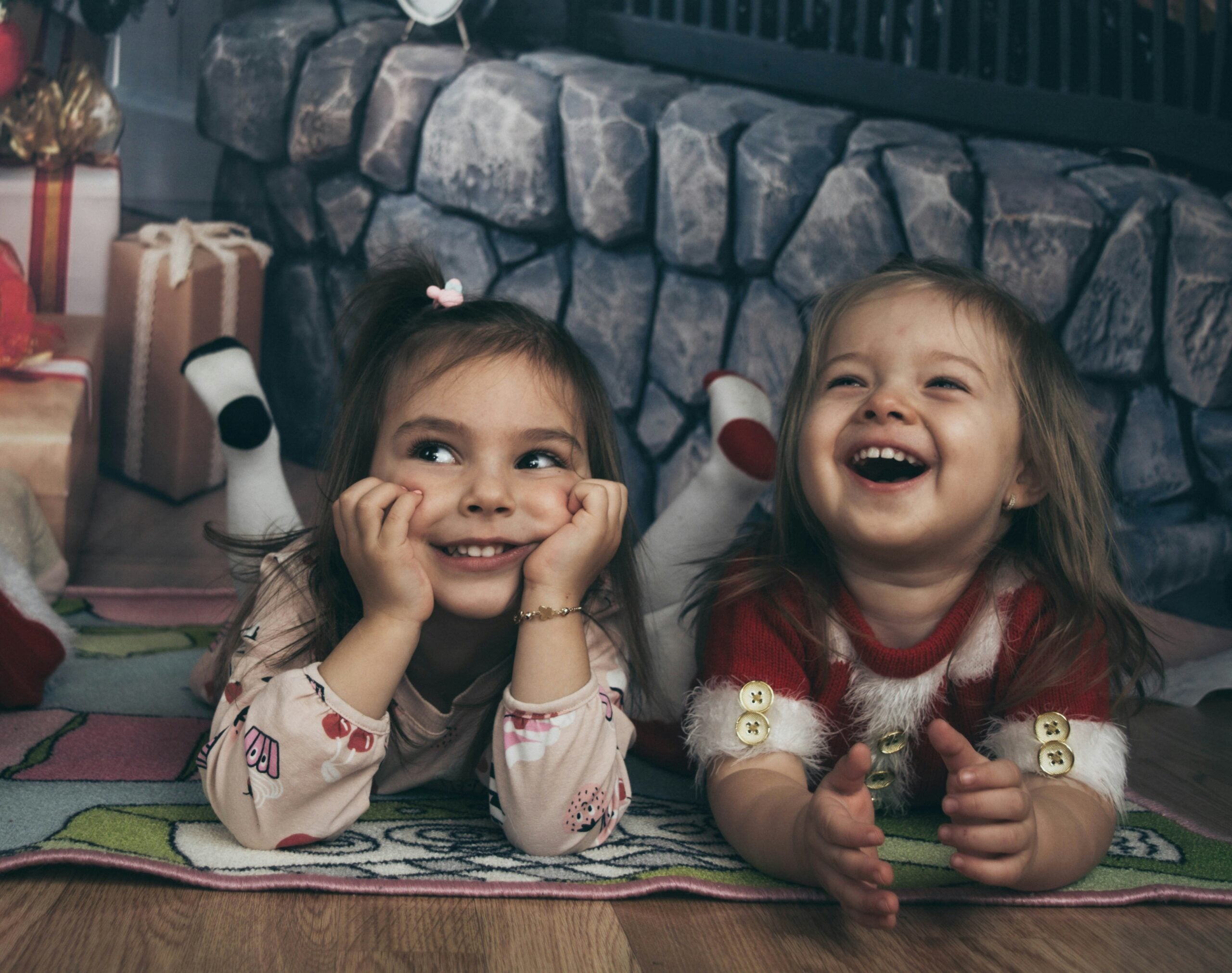 two-little-girls-laying-on-the-floor-next-to-a-christmas-tree
