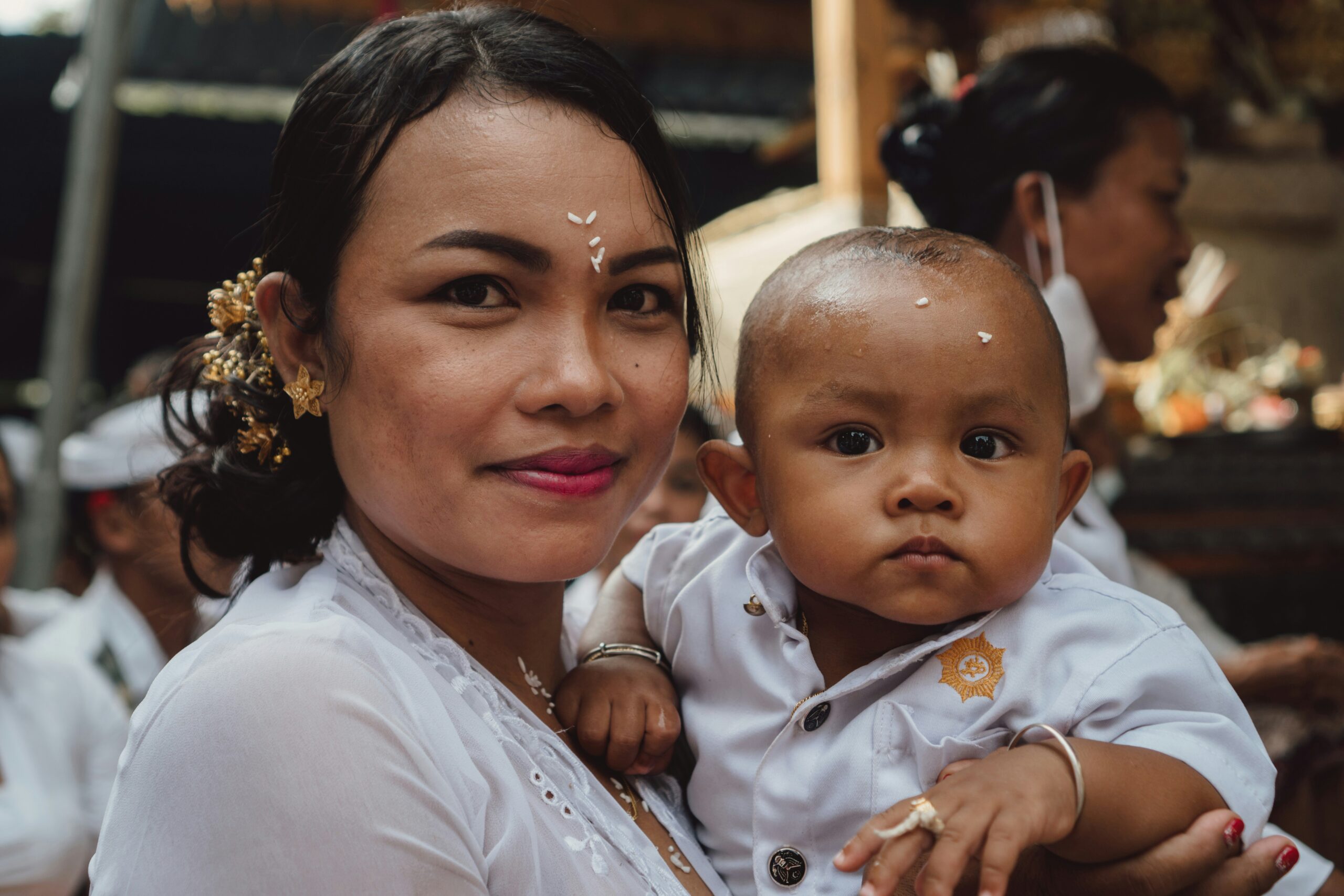 Balinese woman with her son during religious ceremony