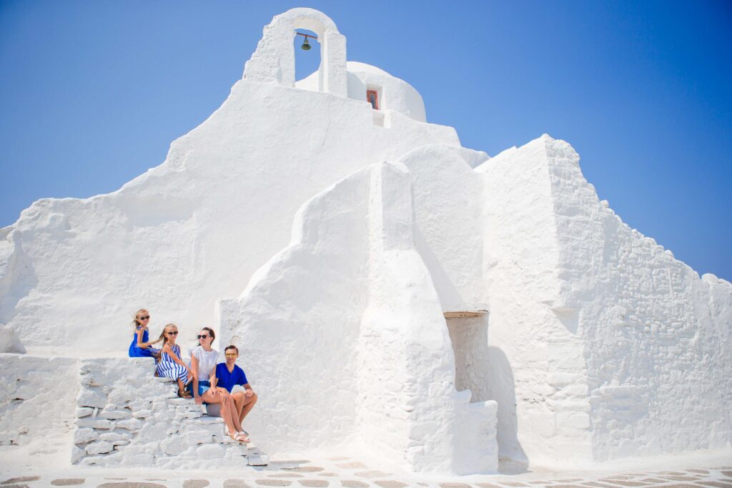 Family of four on the stairs of Paraportiani church on Mykonos Island, in Greece