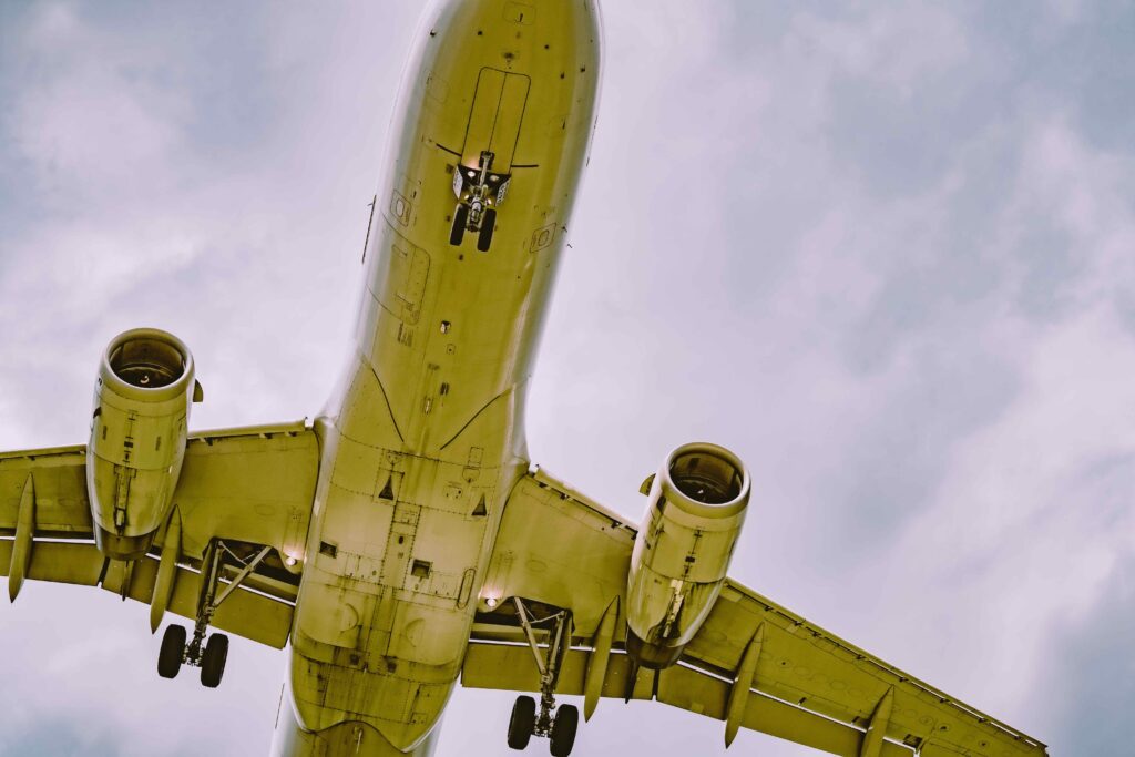 Low angle shot of an airplane flying against a cloudy blue sky