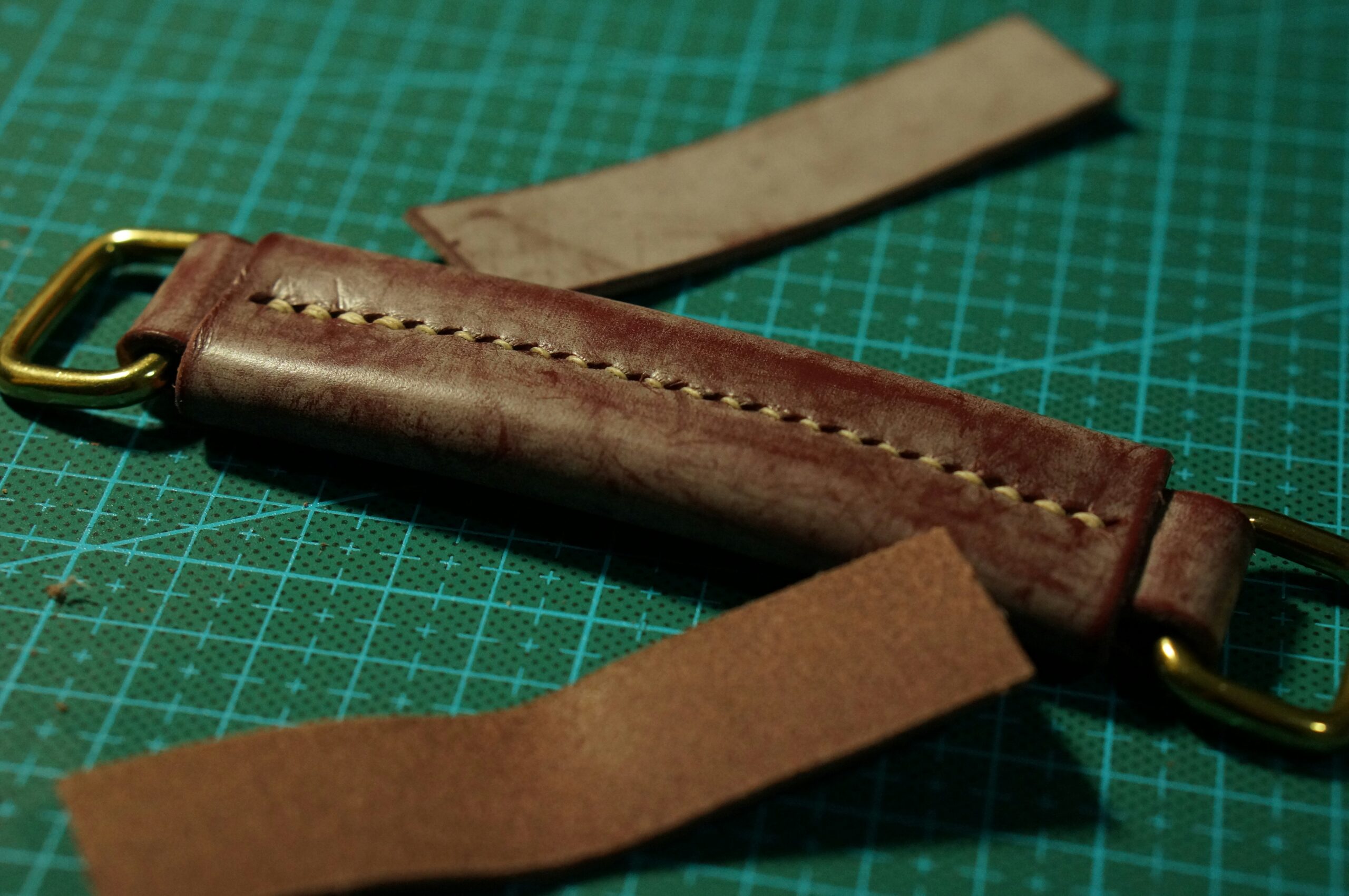 a leather watch strap on a green cutting mat