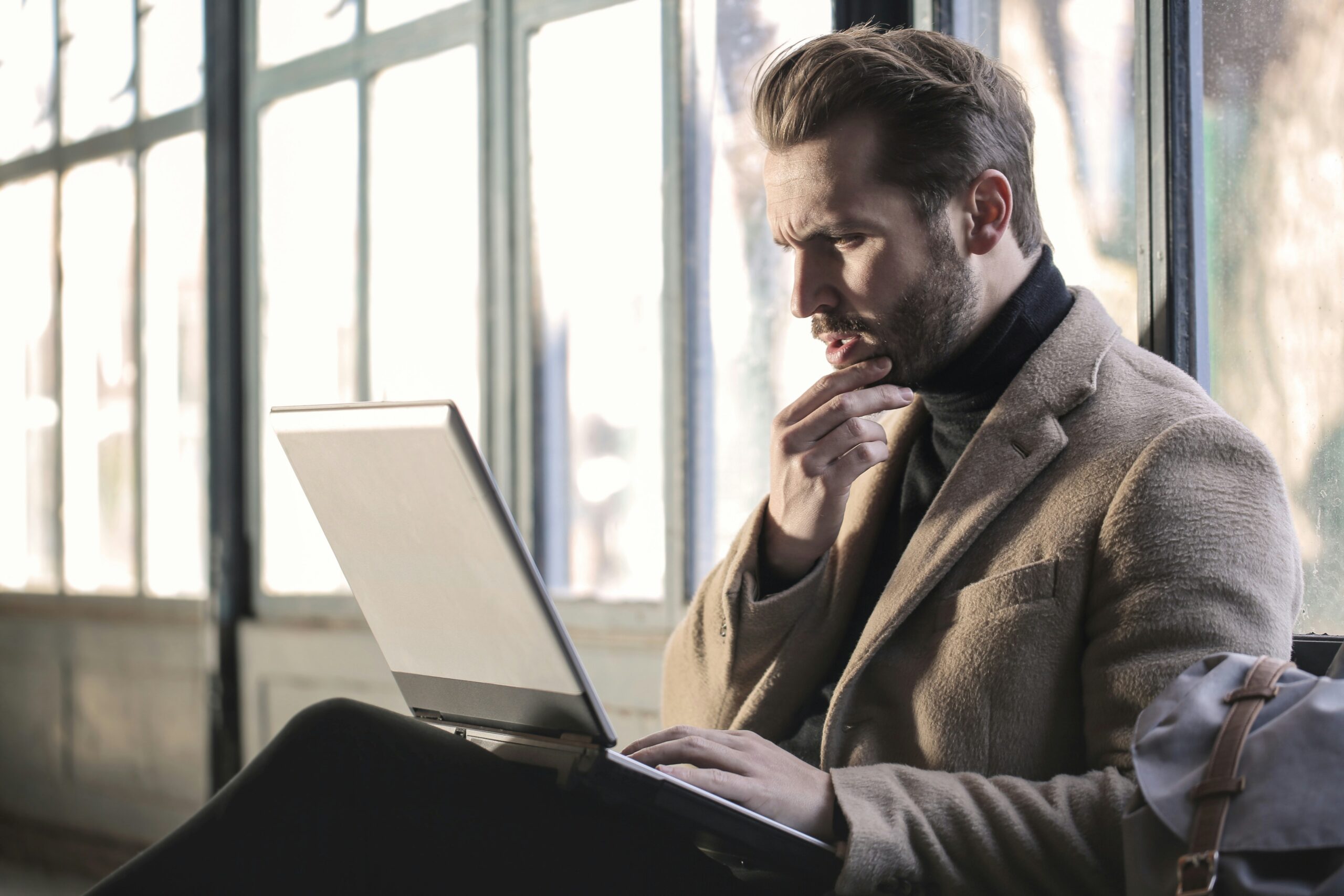 man-holding-his-chin-facing-laptop-computer