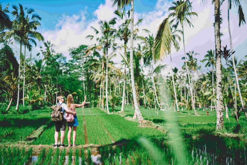 Couple standing in tropical garden and taking selfie