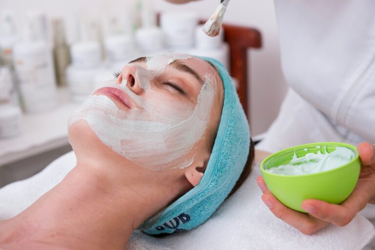 woman-lying-on-blue-towel-with-white-cream-on-face