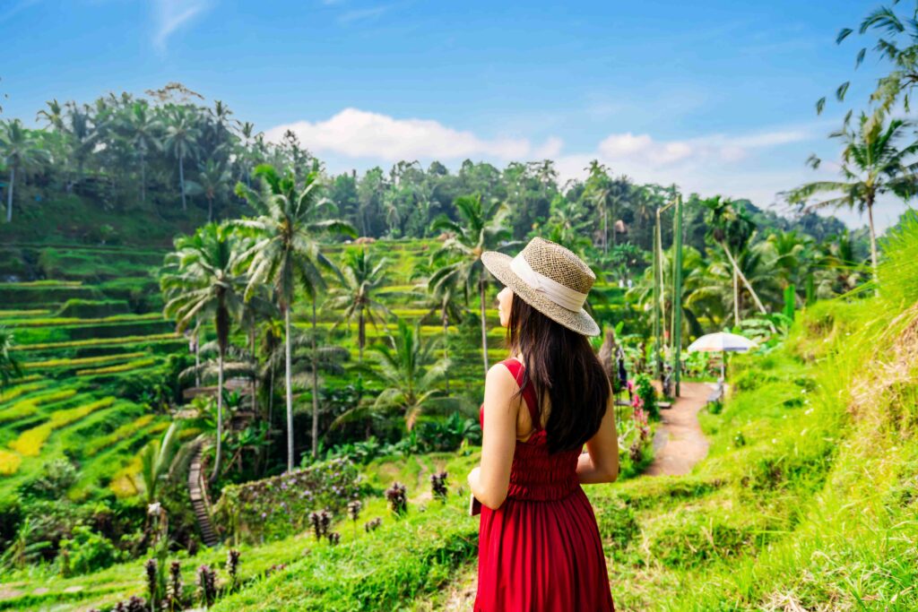 Young female tourist in red dress looking at the beautiful tegalalang rice terrace in Bali, Indonesia