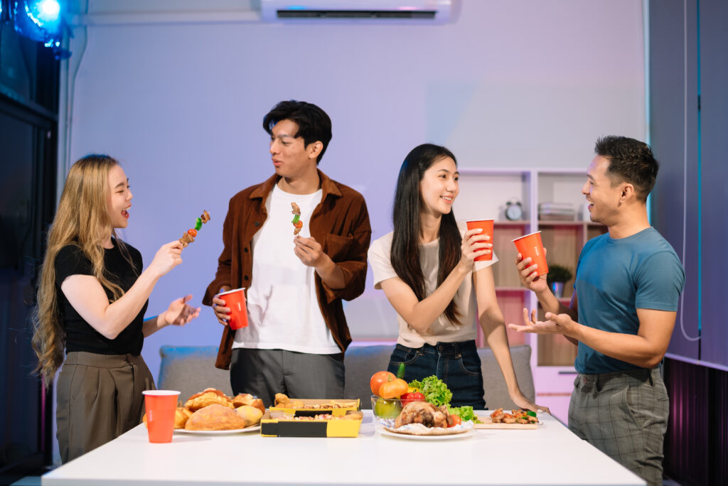 Young Asian Friends Celebrating with Laughter and Food at a Mode