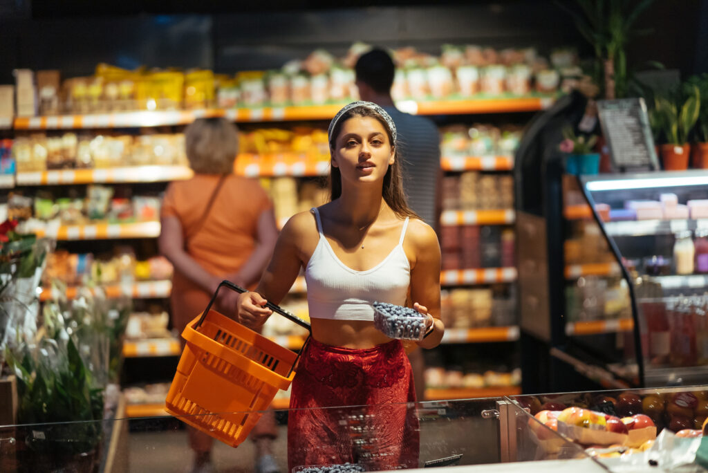 young woman do shopping in supermarket choosing blueberry in store